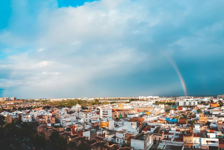 a rainbow appears over a city under a stormy sky