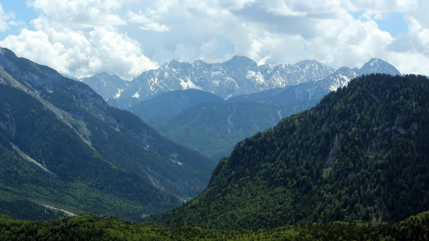 the mountains are covered in snow and lush green