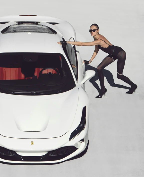 woman in  black dress and sunglasses opening the hood of white sports car