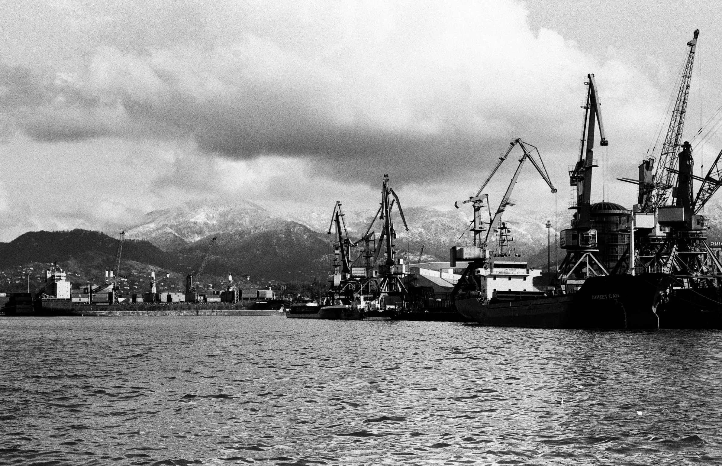 several large ships docked in a harbor on a cloudy day