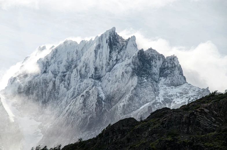 a mountain covered in snow with some clouds