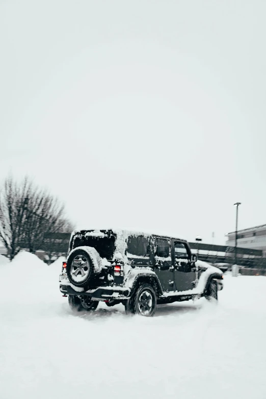 two jeeps are parked in a snow covered parking lot