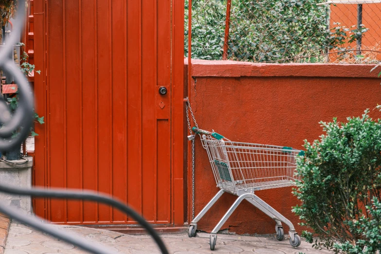 an empty shopping cart sitting in front of red door