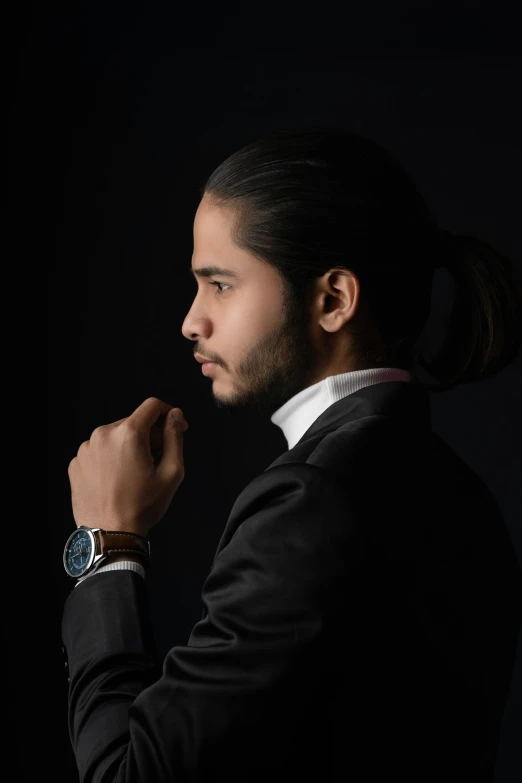 a man with long hair wearing a suit and watch