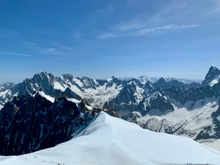 two skiers are on top of a large snowy mountain