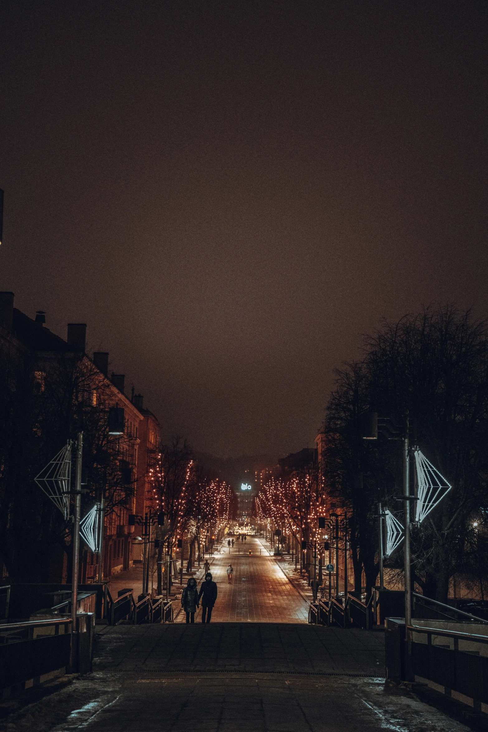 a couple of people are walking down a dark street