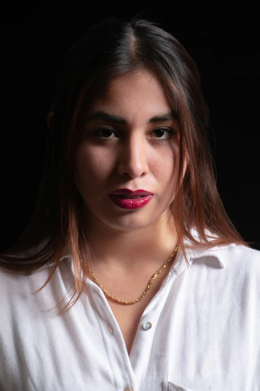 a young woman in a white shirt, wearing a necklace with gold jewelry