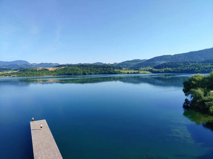 a dock sitting in the middle of a lake next to mountains