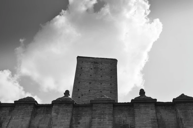 black and white pograph of the old brick wall in front of cloudy sky