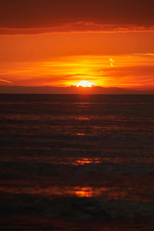 the sun setting on an orange sky over the ocean