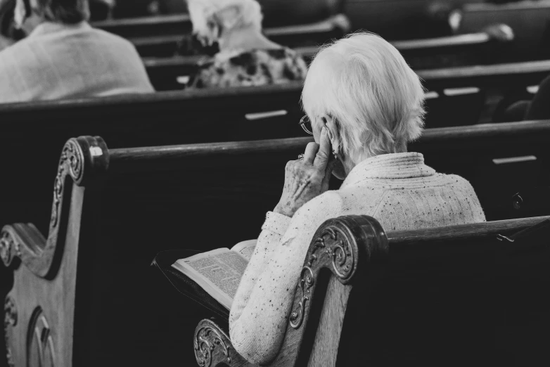 old woman sitting on the seats in a theater, reading a book