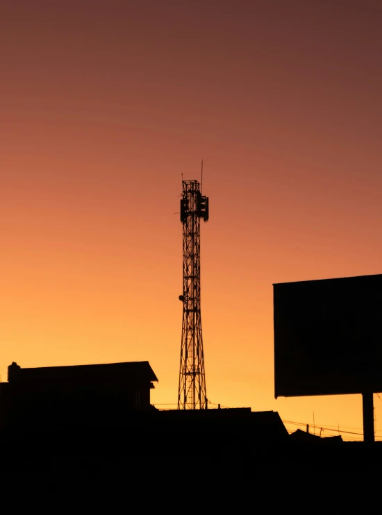 the silhouette of a tower and a building are shown at sunset