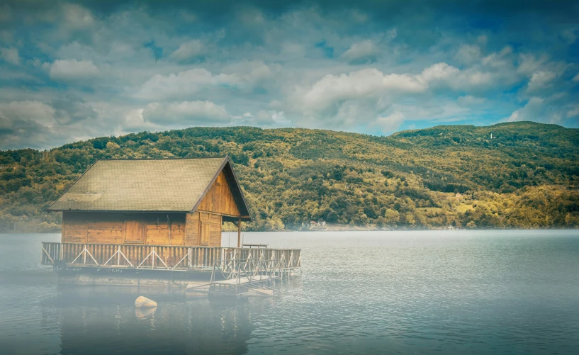 a lake with some clouds near a small house