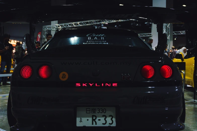 a black car with red rear lights and a crowd watching