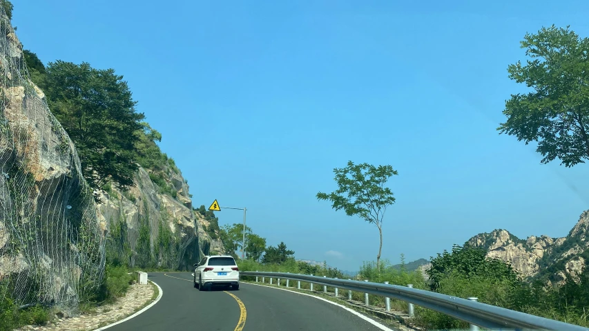 a car driving down a winding road below rock formations