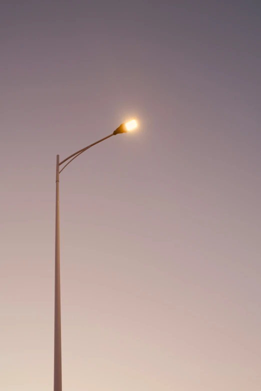 the streetlight is on at the corner of the street