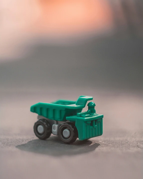 a green toy truck with two plastic cars on a table