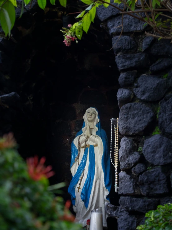 the statue of the virgin mary has a small beaded cross in its hand