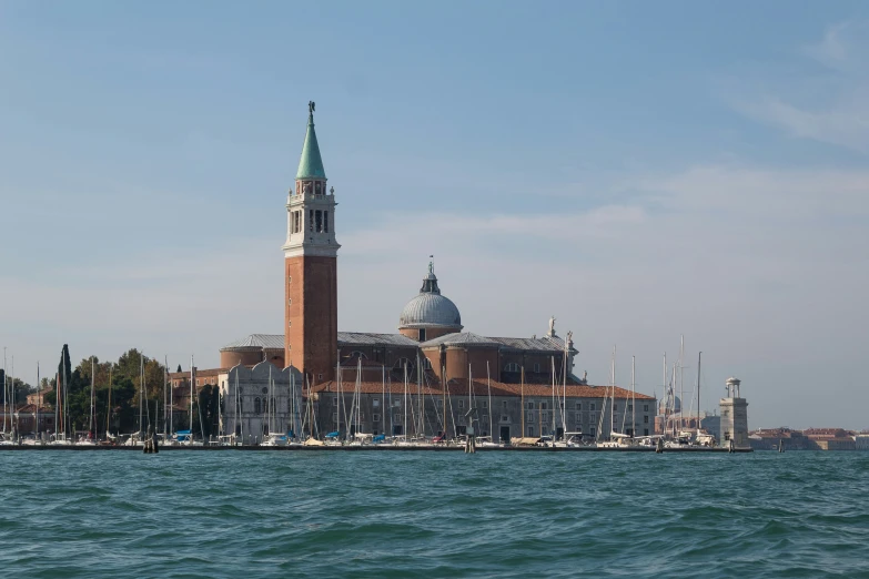 a large building on a beach with boats floating around