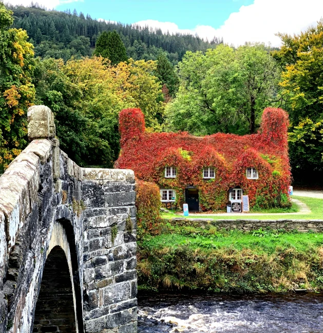 a stone bridge that has a small house in the background