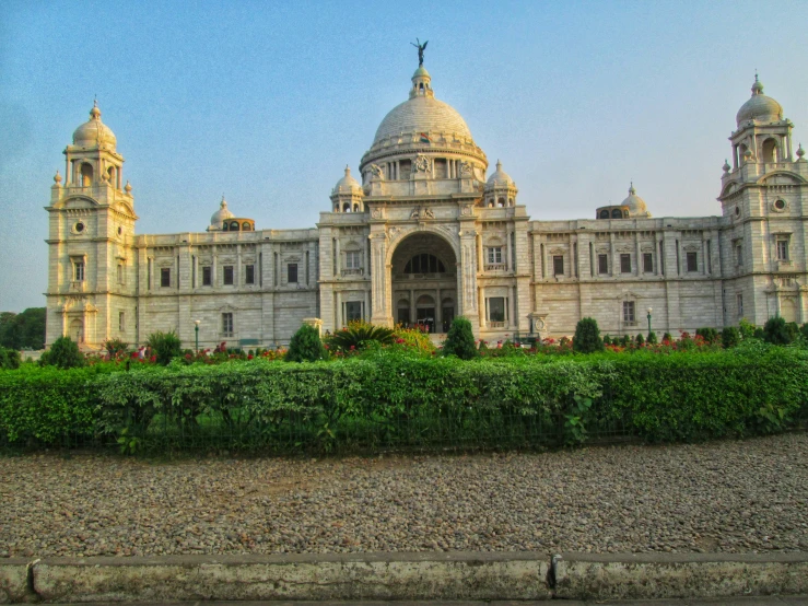 an ornate white building in front of a green hedge