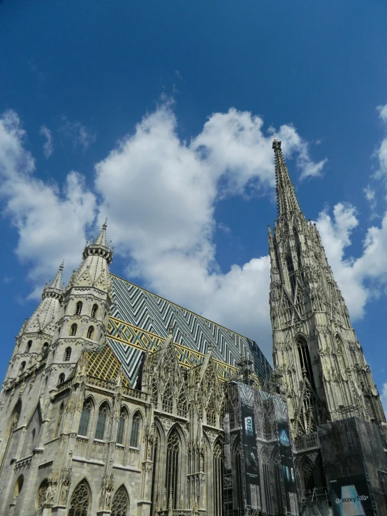 the sky is partly cloudy over a large gothic cathedral