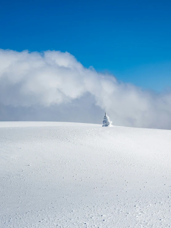 skier on slope in front of cloud covered mountain