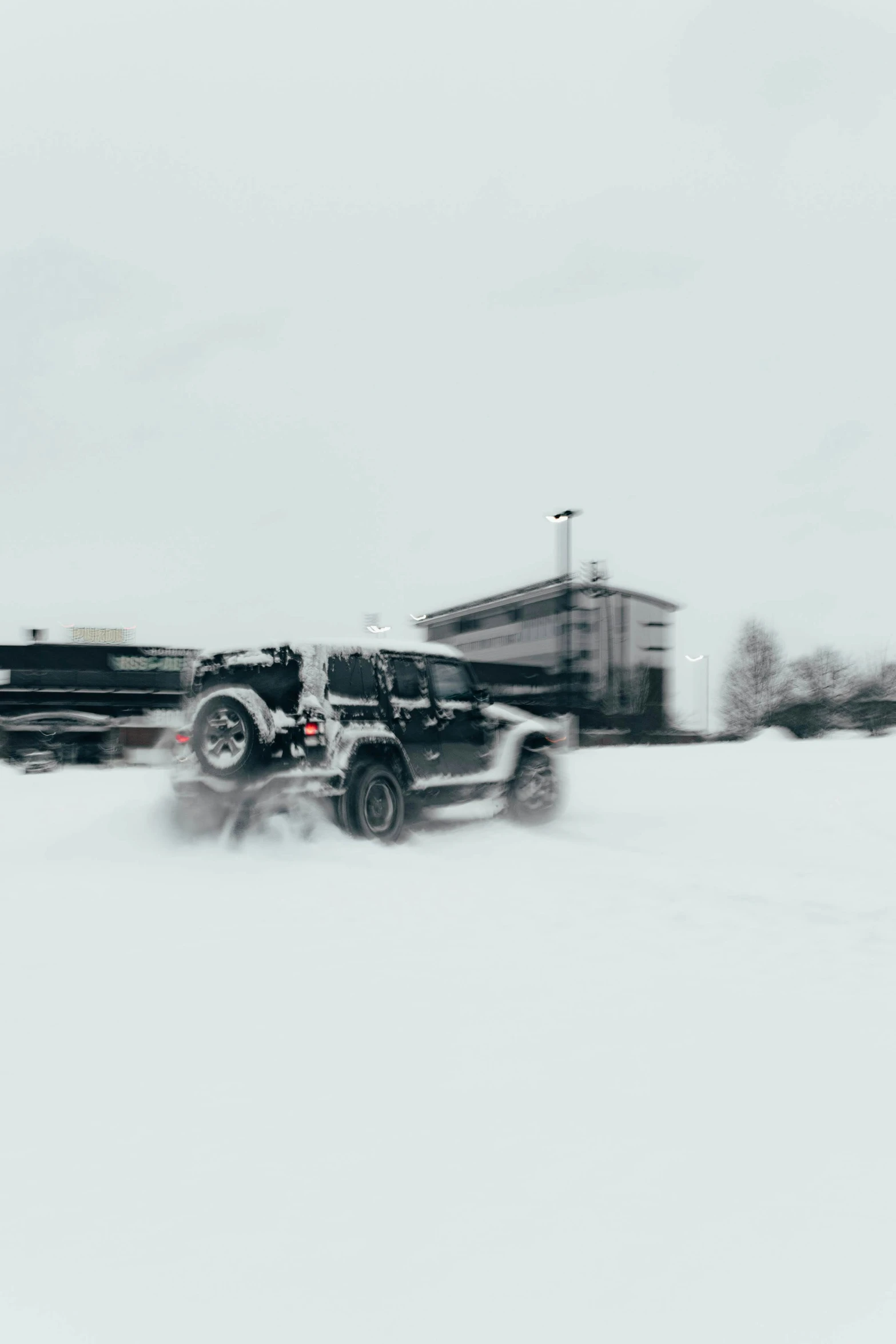 two truck driving through the snow on a cloudy day