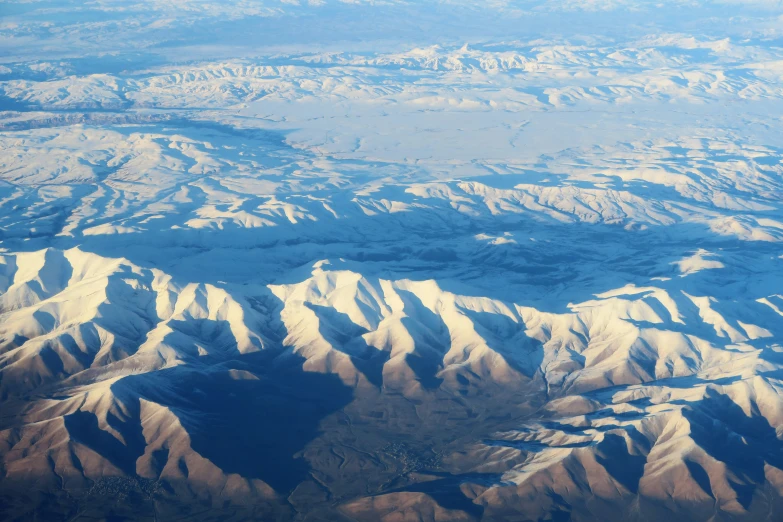 an aerial view shows snow - covered mountains near the ocean