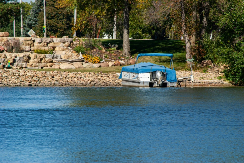 a boat sits in the water by a rocky shore