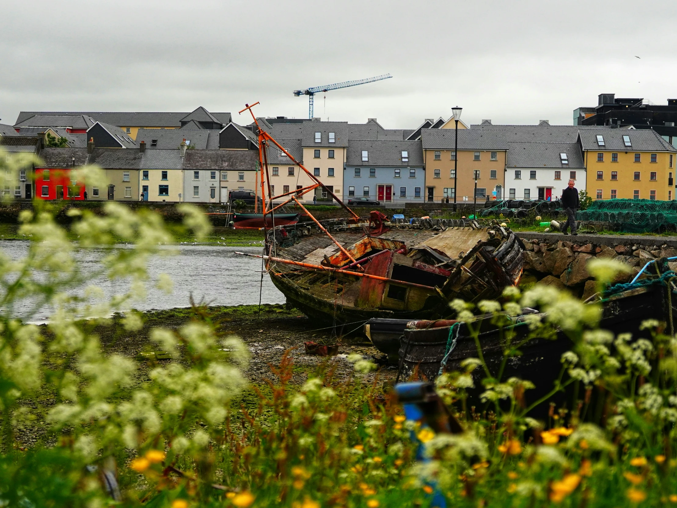 an old boat is sitting on the shore of a bay in front of houses