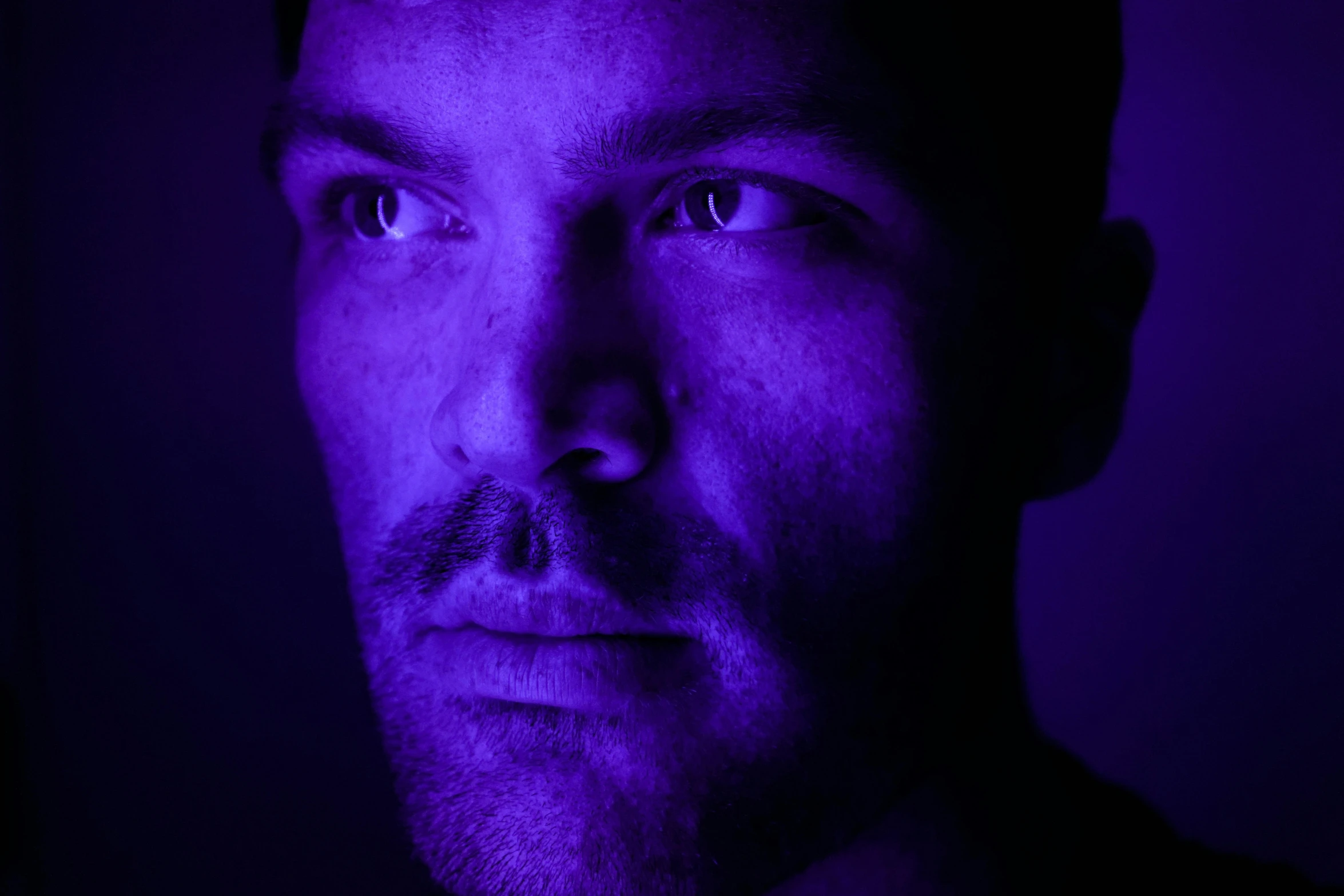 a man with purple lights on is staring straight ahead