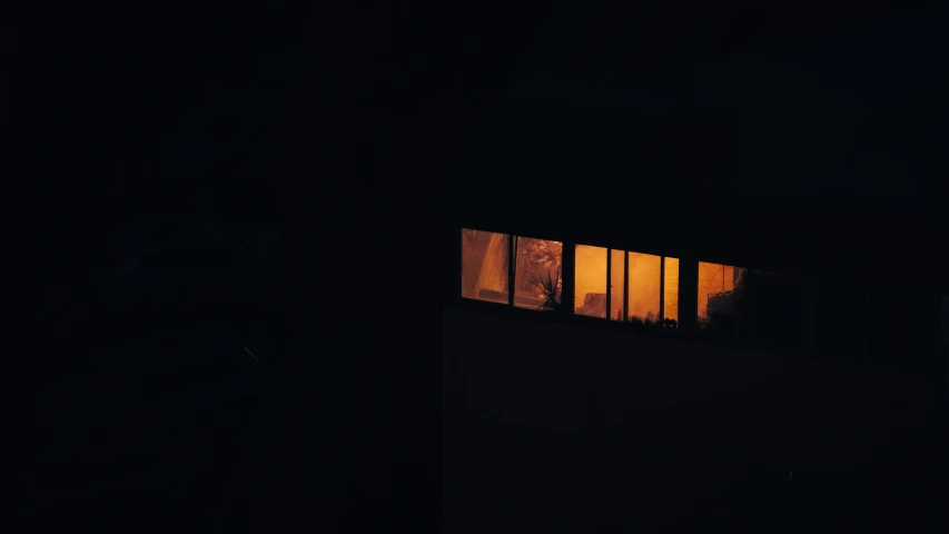 two people standing outside a window at night