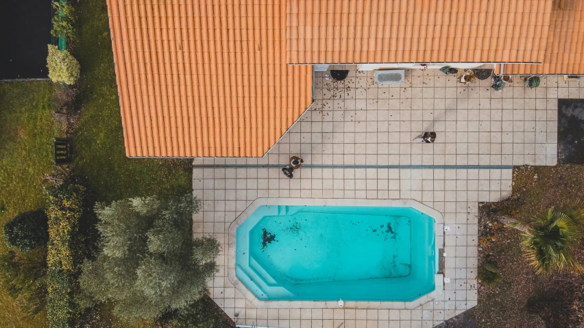 an overhead s of a swimming pool surrounded by a tiled patio