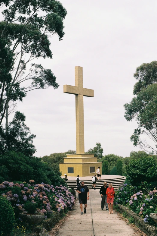 a large cross with three people walking up a pathway