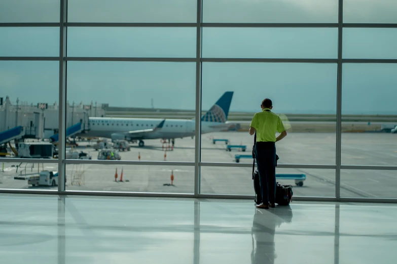 a man standing outside of an airport waiting for his plane to arrive