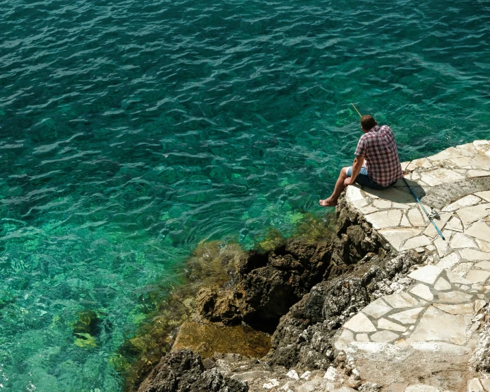 man fishing on a large open blue body of water