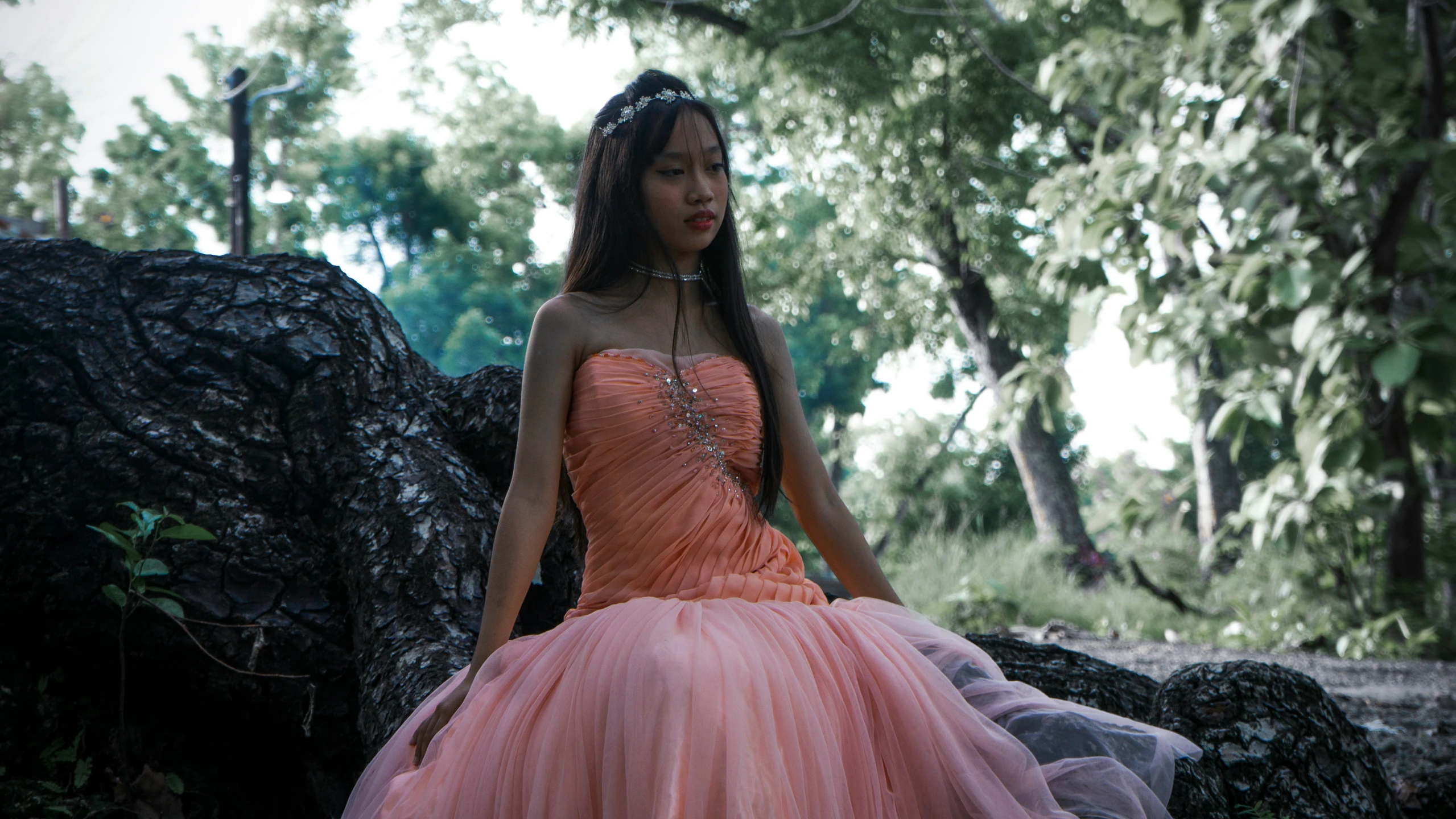 woman in pink dress leaning against the rock