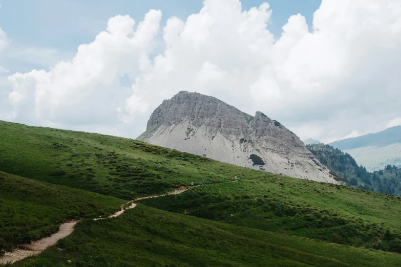 a path up a hill with a green field below