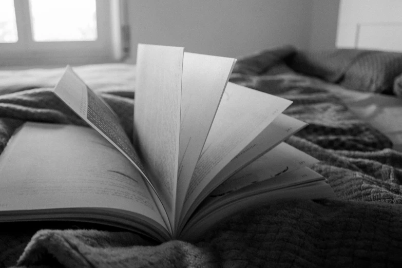 a black and white po of an open book on a bed