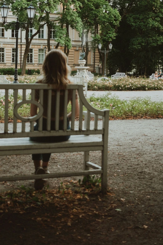 a woman sitting on a white park bench