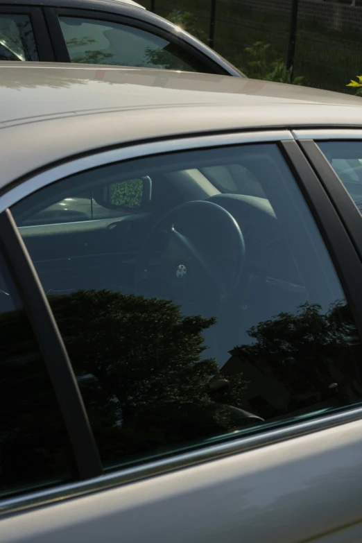 a silver car parked next to another car with a blue sign in its window