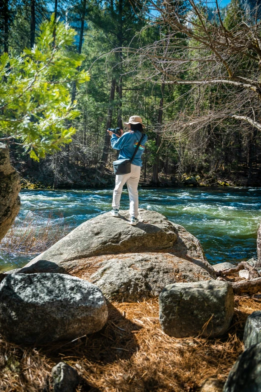 a man stands on a rock over looking a river