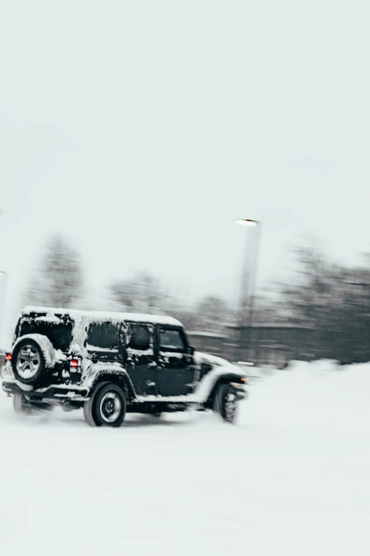 a jeep driving in snow on a cloudy day