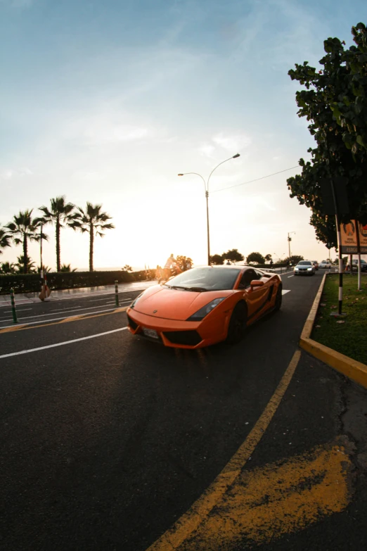 a orange sports car driving down the street in a foreign country