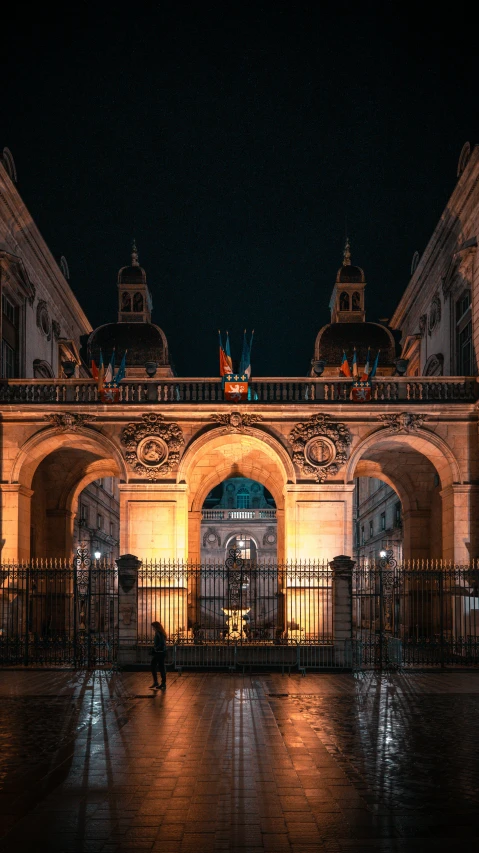 the front gate to a building lit up with lights