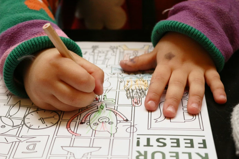 young person coloring a book with an object nearby