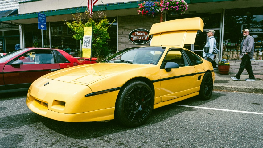 a yellow sports car parked in front of a shop