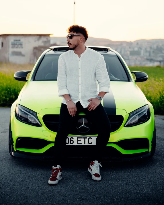 a man sitting on the hood of a bright green car