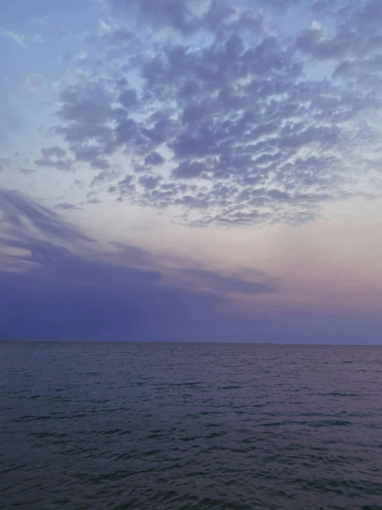 a lone sailboat is docked off the coast at dusk